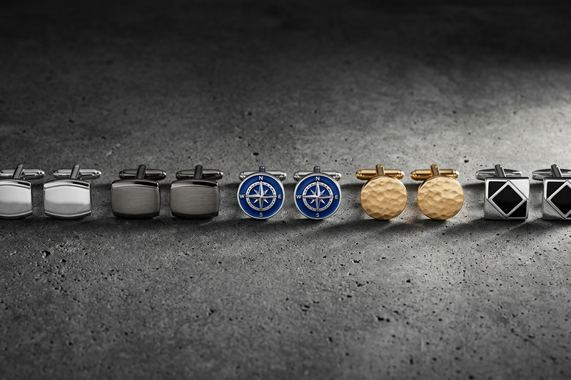 Five pairs of assorted cufflinks arranged in a row showing variety from classic to novelty